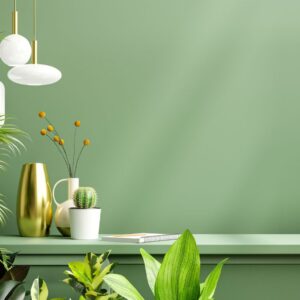 Lush indoor plants styled with gold and white vases on a green counter against a matching green wall.
